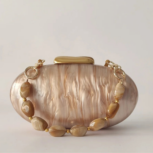Clutch bag with gold chain and shell-like design on a light gray background,