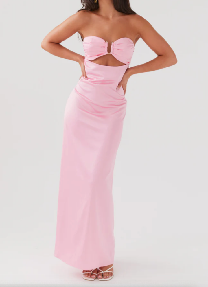 Woman wearing a pink strapless gown with cut-out design on a white background