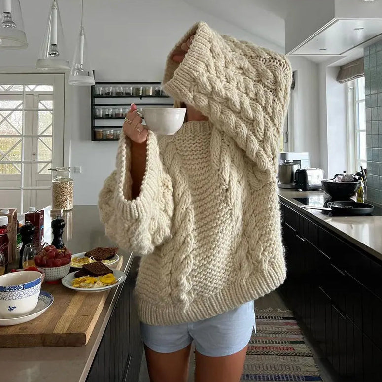 Person wearing a large beige sweater in a kitchen