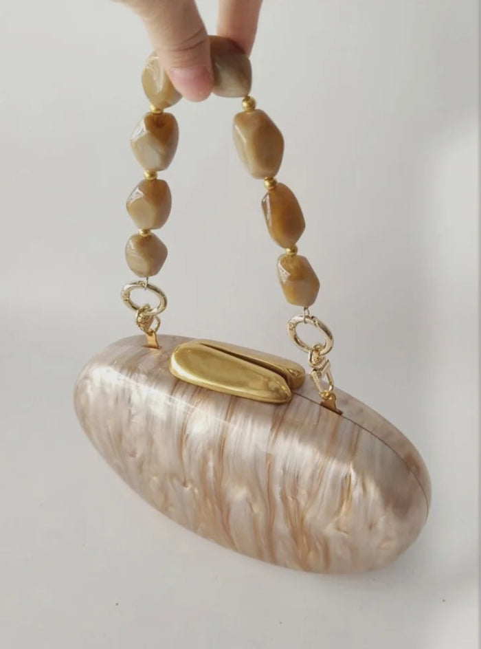 Framed photograph of a hand holding a shell-handled clutch against a light background