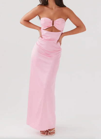 Woman wearing a pink strapless gown with cut-out design on a white background